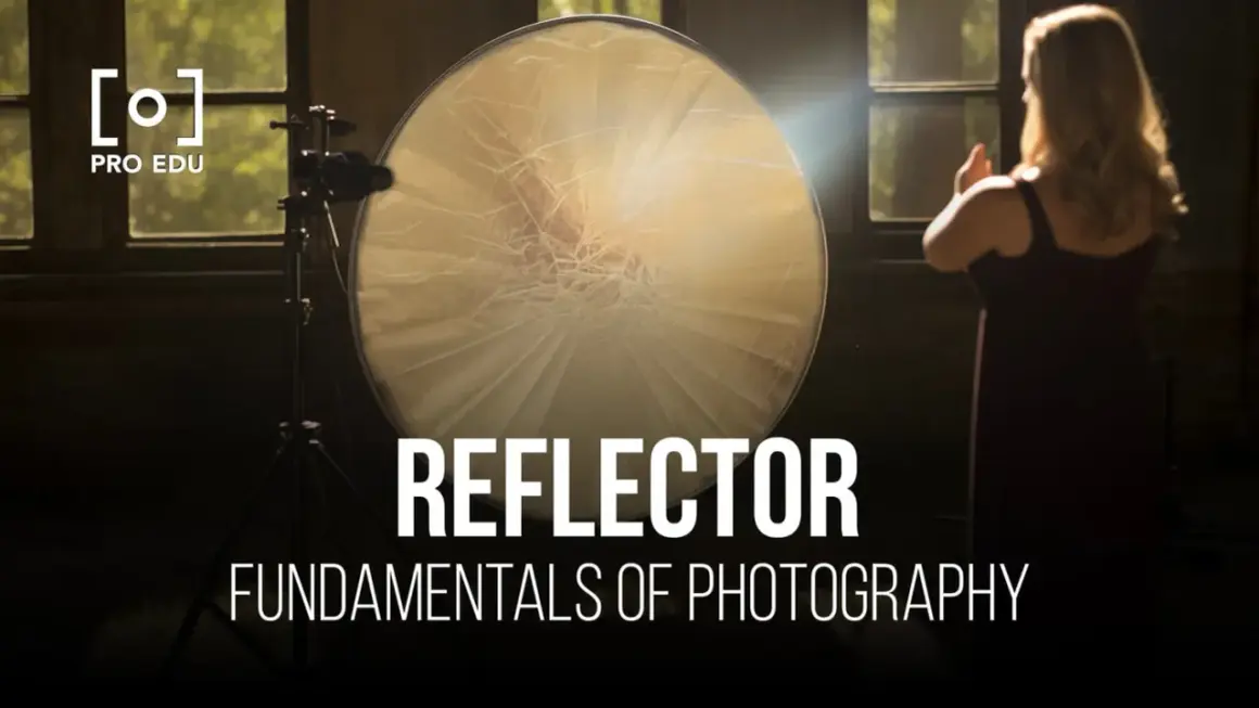 A large, round reflector is used to bounce light in this photography setup. A woman stands in the background, her hands raised.