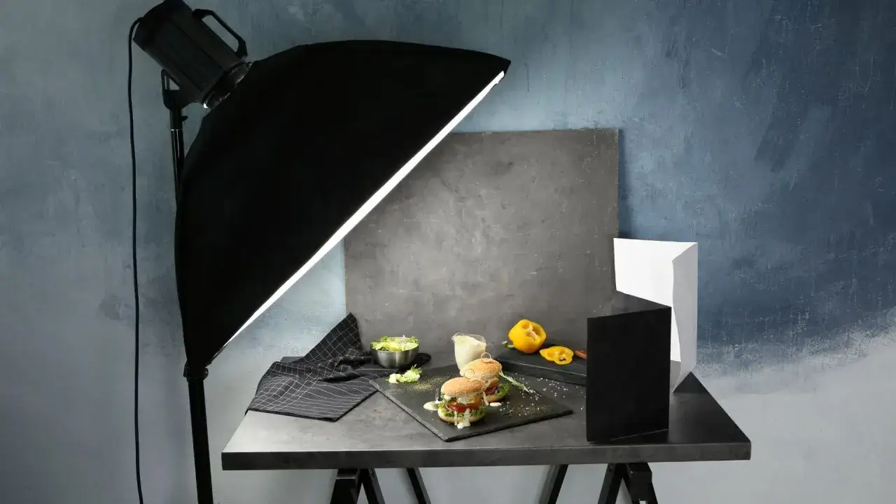 A food photography setup with burgers, salad, and a softbox for DIY photography lighting.