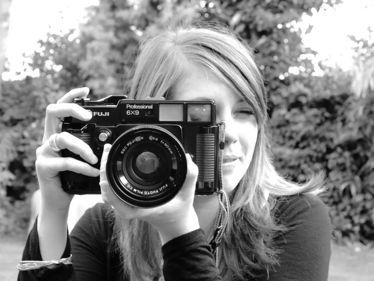 A young woman holds a vintage Fuji 645 Professional 6x9 camera to her eye, ready to capture a moment.