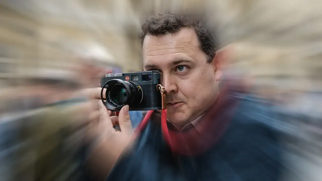 A man with a Leica camera, capturing the essence of 50mm street photography.