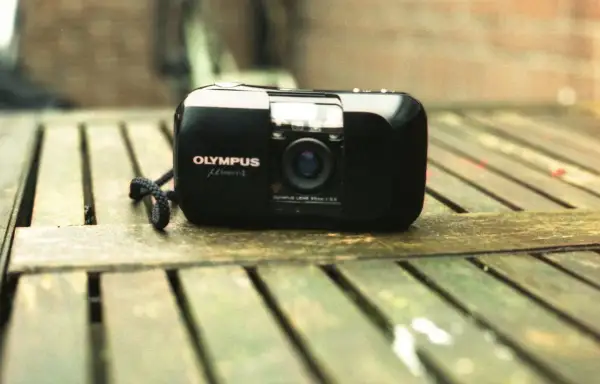 Olympus mju-1 camera, a classic choice for the best film for Olympus Stylus, rests on a weathered wooden surface.
