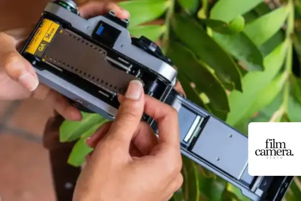 Hands loading a 36-exposure film into a vintage camera. The film roll is visible, ready to capture memories.